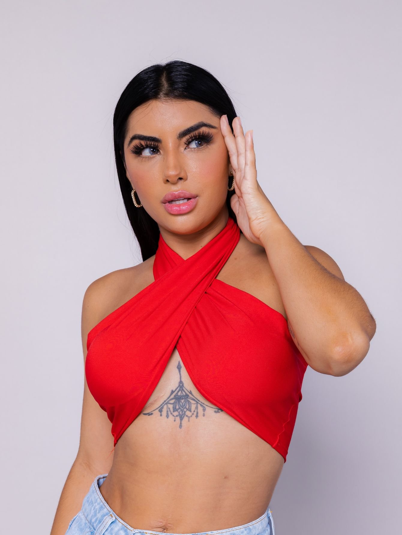 Um modelo feminino com um top preto e um cinto vermelho que diz o nome  nas costas.