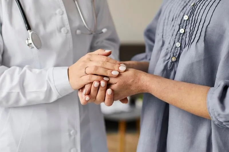 Uma médica segurando a mão de uma paciente