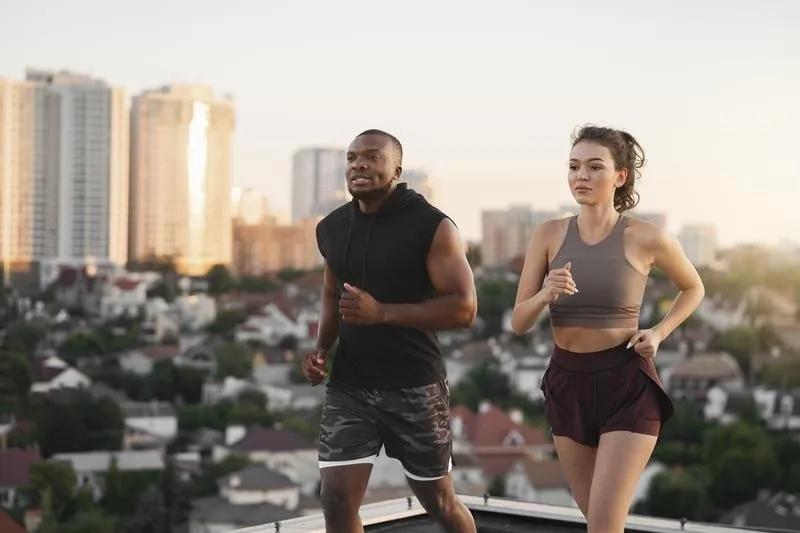 Uma mulher branca e um homem negro caminhando, com roupas esportivas, lado a lado