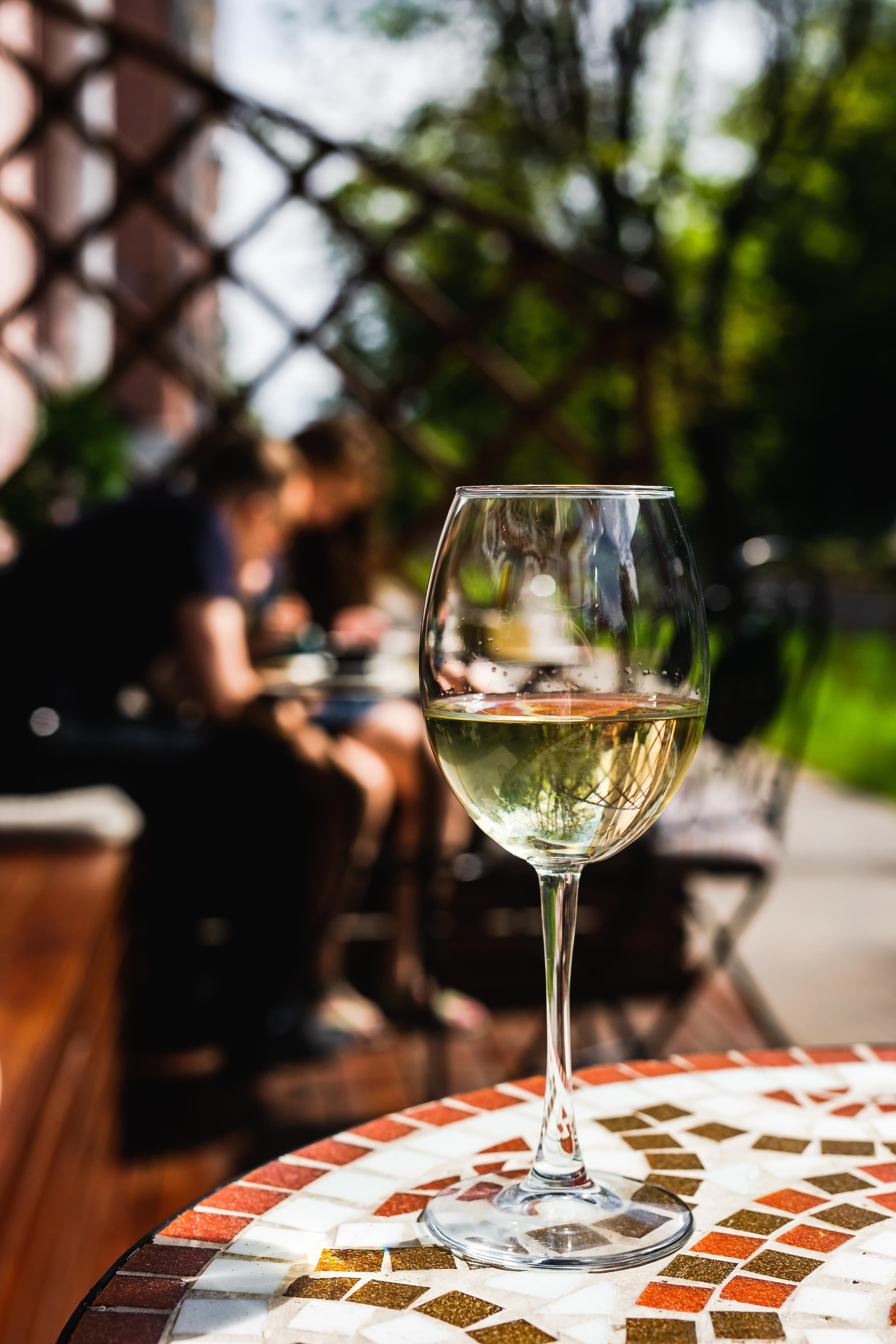 a-glass-of-white-wine-on-a-mosaic-stone-table-of-a-cafe-terrace-on-a-sunny-day-min
